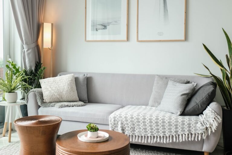 Light-gray upholstered sofa against a white wall with two framed black-and-white photographic prints of an aircraft wing and architectural detail above it.