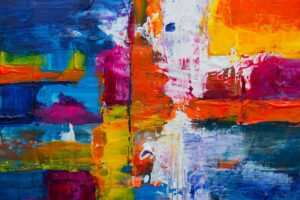 Close-up of a vivid abstract acrylic painting with blue, orange, pink, yellow, and white brush strokes on a textured canvas.