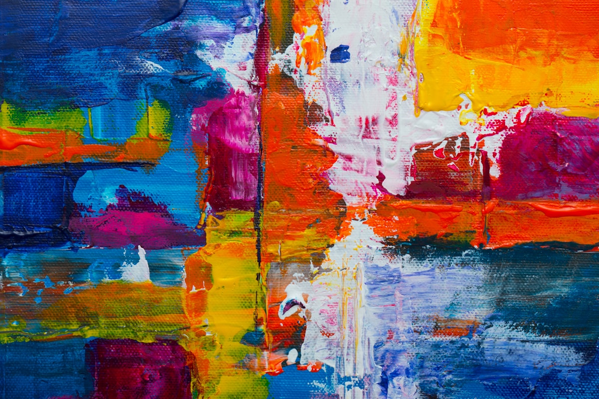 Close-up of a vivid abstract acrylic painting with blue, orange, pink, yellow, and white brush strokes on a textured canvas.